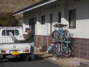 1輪車置き場の前に停めた軽トラックの荷台から工具を取り出す三浦さんの写真