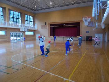 赤白帽子をかぶり、青やグレーの体操服を着た子供たちが体育館内で走りまわっている様子を写した写真