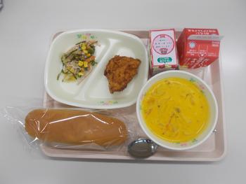 トレーに袋に入ったパン、ポタージュ、お皿にフライドチキン、サラダ、飲み物などが置かれている給食の写真