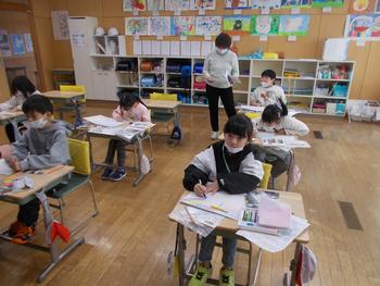 数名の児童が個別に机に向かい、学習プリントやノートに取り組んでいる室内を写した写真