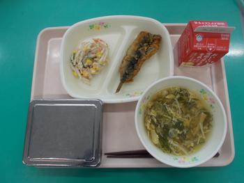 トレーにのせられた、白身魚のフライ、サラダ、スープ、牛乳パック、ご飯が銀色の容器に入っている給食の写真