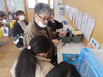 教室内で薬剤師の尾形先生が空気と照度の検査を行っているのを子供達が興味深そうに見ている写真