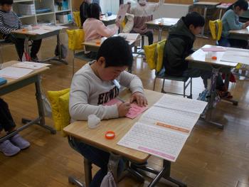 教室で小学生たちが自分の机で何かに熱心に書き込みながら、集中して授業に取り組んでいる様子の写真