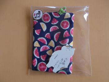透明のラッピング袋に入った、スイカ柄の巾着に、猫の形をした「六年間ありがとうございました。」と書かれたメッセージカードが添えられている写真