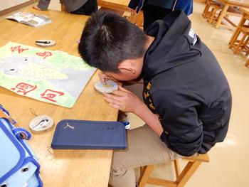 教室で男の子が木の円盤に細かい作業を集中して行っている様子の写真