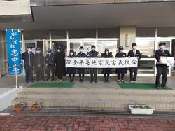 校舎の前で生徒たちが「能登半島地震災害義援金」の横断幕を持って横一列に並んで立ち、右端の生徒が募金箱、左端の生徒が「がんばれ志中生」の青いのぼり旗を持っている写真