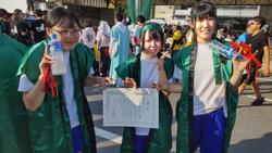 屋外で緑の法被を着た女子生徒が3人並び、中央の生徒が賞状を手にもって記念撮影をしている写真