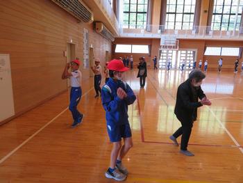 体育館で子どもたちと高齢の方が一緒に体操をしている様子の写真