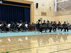 大勢の生徒たちが楽器を持って椅子に座っている、台湾楽団の演奏パフォーマンスの写真