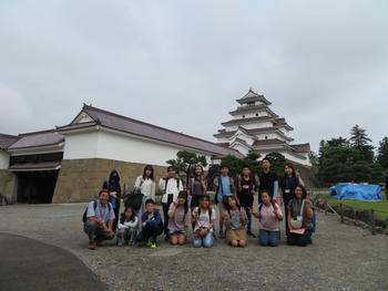 白いお城を背景に、楽しそうな表情の児童たちと教職員らが集まった集合写真