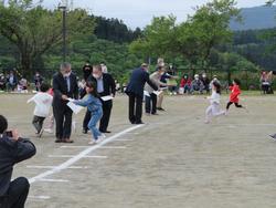 グランドに白線が引かれゴールした子どもたちが景品をもらっている新1年生のかけっこの写真