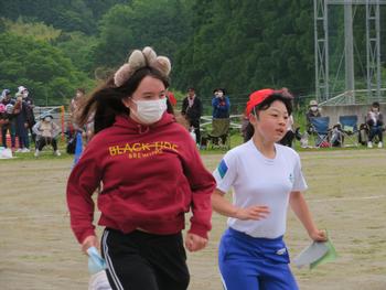 耳のようなものがついたカチューシャをつけた女性と赤い帽子の女子児童が並走している写真