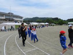 運動場のカーブしたトラックを、保護者と児童たちが一緒に入谷小唄を踊りながら歩いている写真