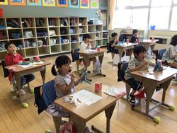 生徒たちが各自の机に座り、歯ブラシを手に持ち、歯磨き指導を受けている様子の写真