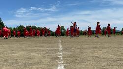 赤い服を着た多くの生徒たちがグラウンドに広がり踊りを踊っている写真