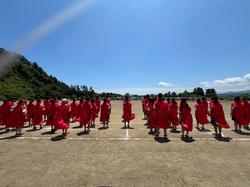 運動会で、赤い法被を着たたくさんの生徒たちが、グラウンドに整列して立っている様子の写真