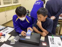 実験室で二人の生徒が測定器を使って作業しながら確認している写真