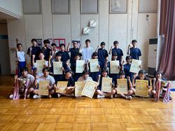 多数の学生たちが賞状やトロフィー、メダルなどを手に、笑顔で並んだ集合写真