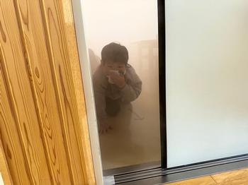 煙が立ち込める室内から四つん這いになりハンカチで口をふさいで避難訓練をおこなっている男子児童の写真