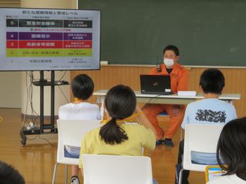 消防隊員の人がモニターを使い説明をし、子供たちが真剣に話を聞いている教室内の写真