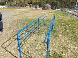 校庭に青色をした手すりが2つ平行に並んでいる一輪車練習用の手すりの写真