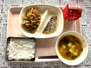 ピンクのトレーに給食が左から時計回りにれんこんきんぴら、さわらのみそマヨネーズ焼き、牛乳、わかめとじゃがいものみそ汁、ごはんと並んでいる写真