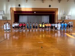 体育館の舞台を背に、ユニフォームを着た生徒たちが各部活動ごとに整列して立っている写真