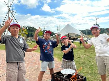4名の子どもたちが飯ごう体験の中ピースをしながら記念撮影をしている写真