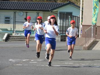数名の高学年の児童が建物の前を懸命に走っている様子の写真