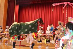 中央には獅子舞が大きく写っており、その周囲には華やかな衣装を着た子どもたちが太鼓を演奏しながら並んでいる写真