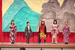 舞台の背景には、山と岩が描かれた手作りの大きな壁画があり5人の児童が和服や特別な衣装を身に着けステージ上に立っている舞台発表の写真