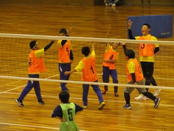 奥のオレンジ色のビブスの男子チーム6名がハイタッチをして喜んでいる様子の写真