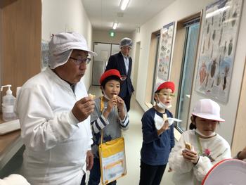 工場の廊下でもらった試食を口にしている子供たちの写真
