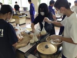 生徒たちが家庭科室の調理台で袋に小分けした材料を鍋から取り出して作業をしている様子の写真