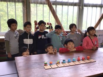 出来上がったオクトパス君9個を中央に並べた机の後ろに9人の児童が並んで記念撮影をしている様子の写真