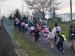 上りの坂道をランドセルを背負った20人程の児童が歩いている様子の写真