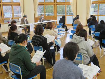 保護者の方が椅子に座りながら資料を見ている様子を室内の斜め後方から写した写真