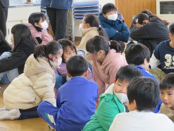 児童たちが床に座り、3～5人程度の小グループに分かれて互いに顔を見合わせながら会話している様子を写した写真