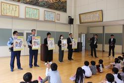 警察官たちが床に座った生徒たちの前でパネルを見せながら不審者対応の指導をしている様子の写真