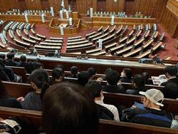 大勢の人が傍聴席に座って、議会本会議場で行われている議論を静かに見守っている様子の写真