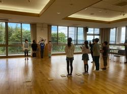 木の床の広い部屋で子どもたちが4人ずつ横一列に向かい合って並び、団結式が行われている様子の写真