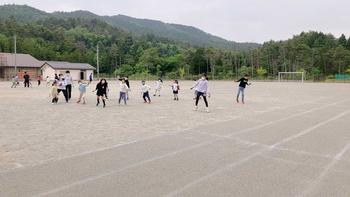 子ども達と先生が運動場に並んで体を横に倒し練習する、よさこいの練習風景を撮影した写真