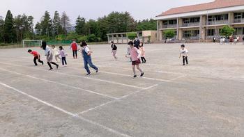 子ども達が運動場に並んで体を前に倒して練習する、よさこいの練習風景を撮影した写真