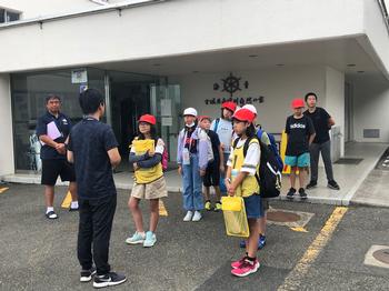 玄関前に並んで先生の説明を聞いている子供たちの写真