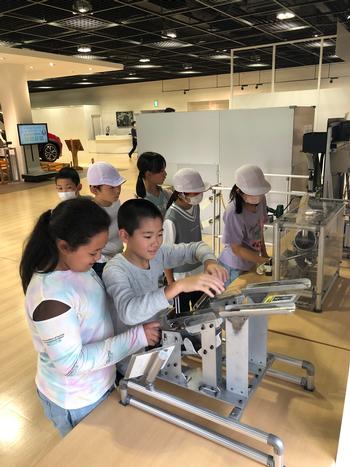 数名の子供たちが機械を触ったりして見学をしている写真