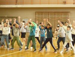 体育館で横3列になり両手をあげてダンスをしている様子の写真