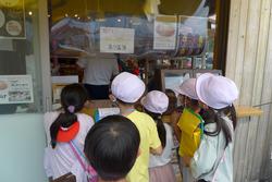 白の帽子をかぶった子どもたちが数人で店先に並び、カウンター越しに店員の方と話をしている様子の写真