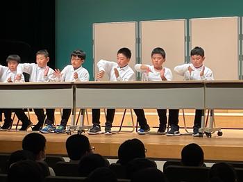 長机に1列に座りカップスの演奏をしている生徒たちをアップで写した写真