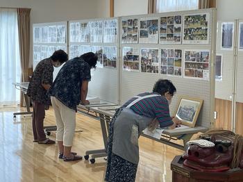 たくさんの写真がはられた大きなボードを3つつなげ、その下には長机が並べられて女性3名が写真を覗き込んでいる様子を写した写真