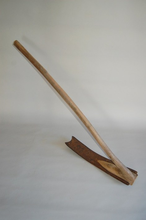 木の柄と湾曲した一枚刃が組み合わされた農具の平鍬の写真